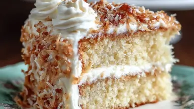 Delicious Coconut Cake with Cream Cheese Coconut Frosting decorated with coconut flakes.