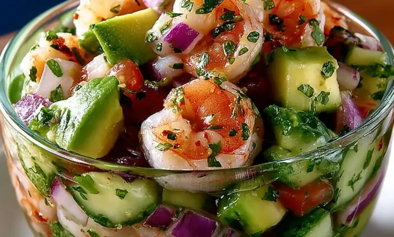 Colorful Mexican shrimp cocktail served in a glass with fresh lime and avocado.