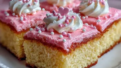 Pink Vanilla Cake Squares topped with frosting on a white plate