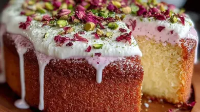 Delicious homemade rose milk cake topped with cream and rose petals.