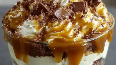Delicious caramel cheesecake brownie trifle dessert with layers of chocolate and cream.