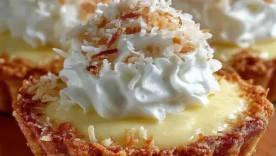 Delicious mini coconut cream pies topped with whipped cream and coconut flakes.