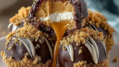 No-bake peanut butter cheesecake balls on a plate, drizzled with chocolate.