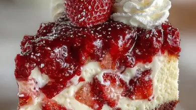 Slice of decadent Red Velvet Strawberry Cheesecake topped with strawberries