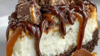 Delicious homemade Snickers Cheesecake topped with chocolate and caramel