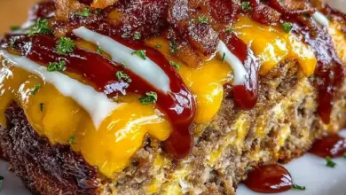 Bacon Cheeseburger Meatloaf topped with cheese, served with a side of vegetables