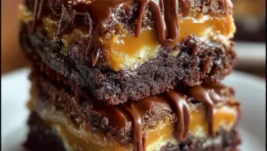 Delicious Snickers Brownie Bars topped with caramel and peanuts