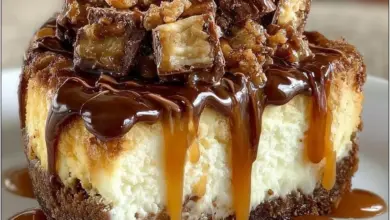 Delicious homemade Snickers Cheesecake topped with caramel and chocolate